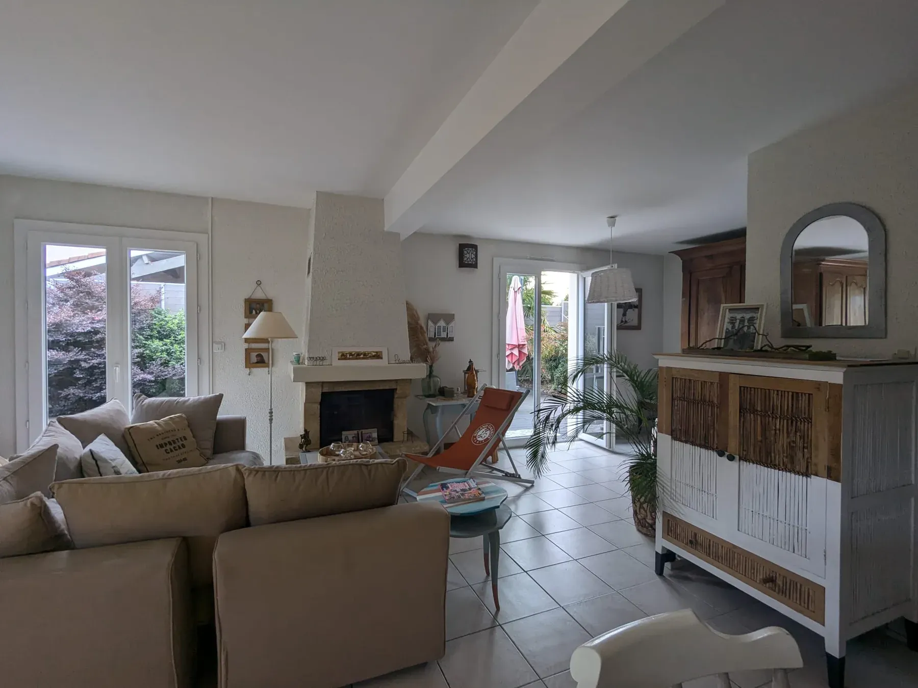 Séjour existant avec cheminée, canapé beige et sol carrelé