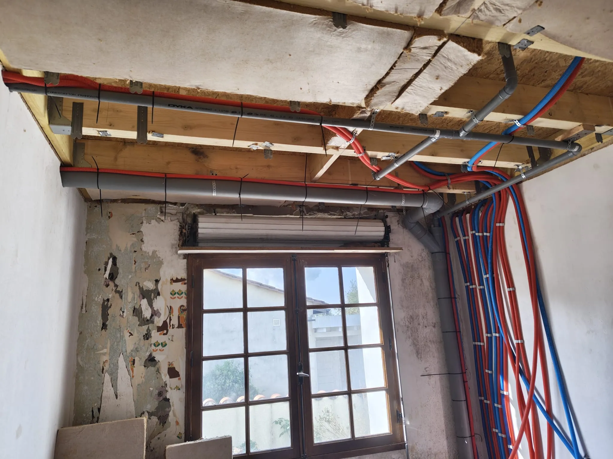Canalisations et conduites visibles dans un plafond ouvert au-dessus d’une fenêtre