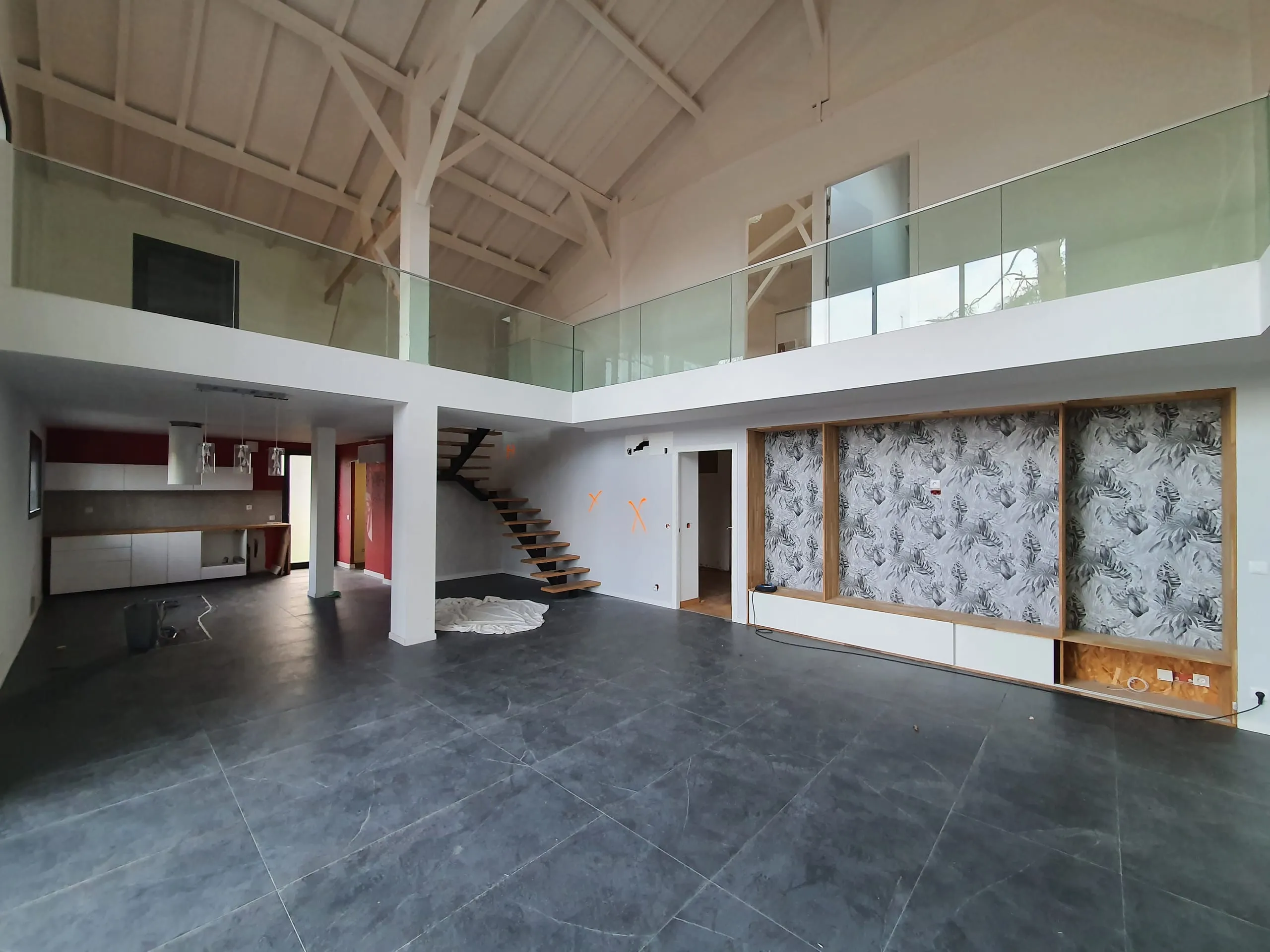 Pièce de vie à double hauteur avec mezzanine vitrée, escalier ouvert et aménagement mural botanique